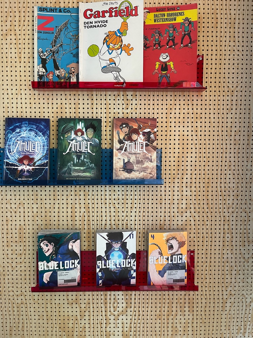 Tegneserier præsenteret på pegboard med farvede akrylhylder